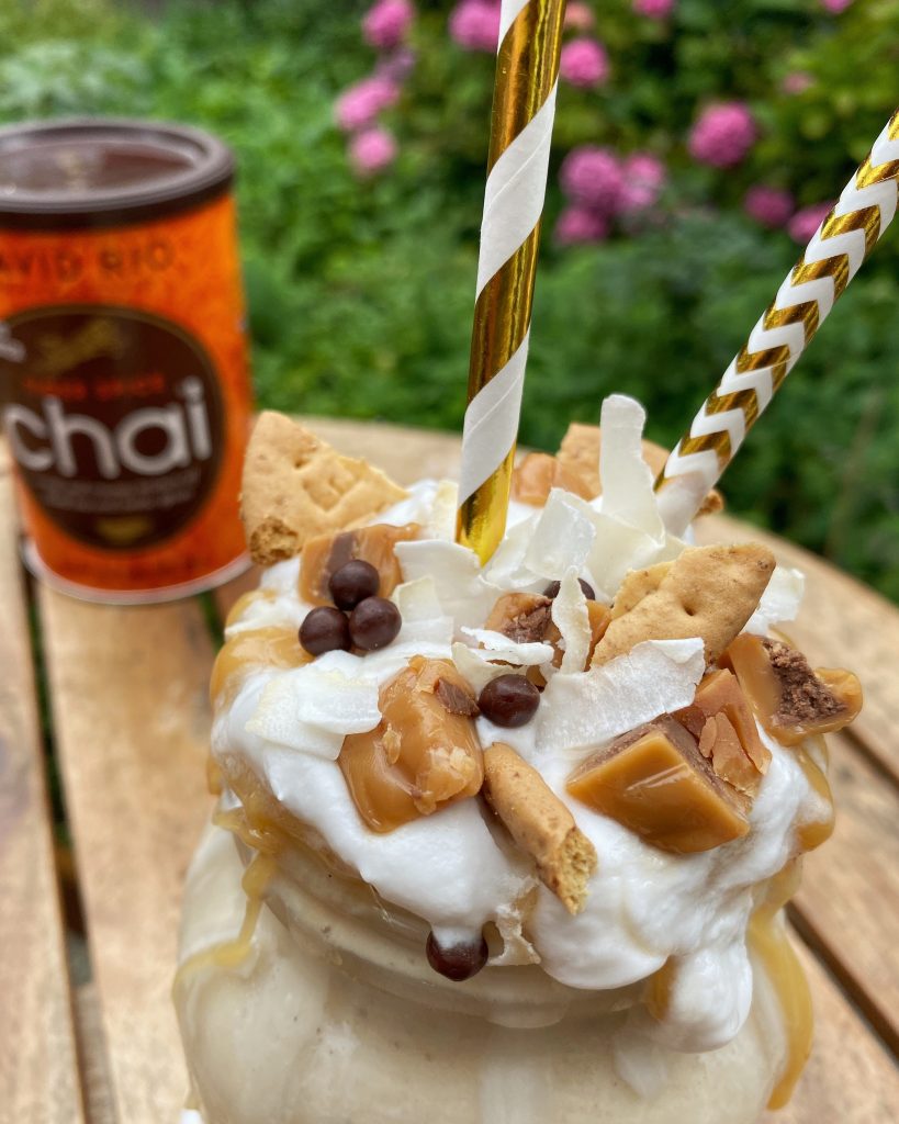 close up of a milkshake with toppings and a can of David Rio chai mix