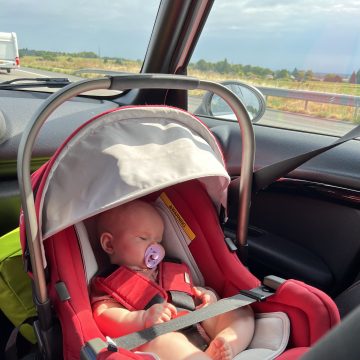 baby in red car seat sleeping in car
