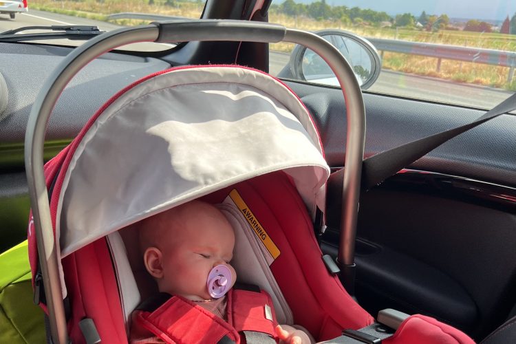 baby in red car seat sleeping in car